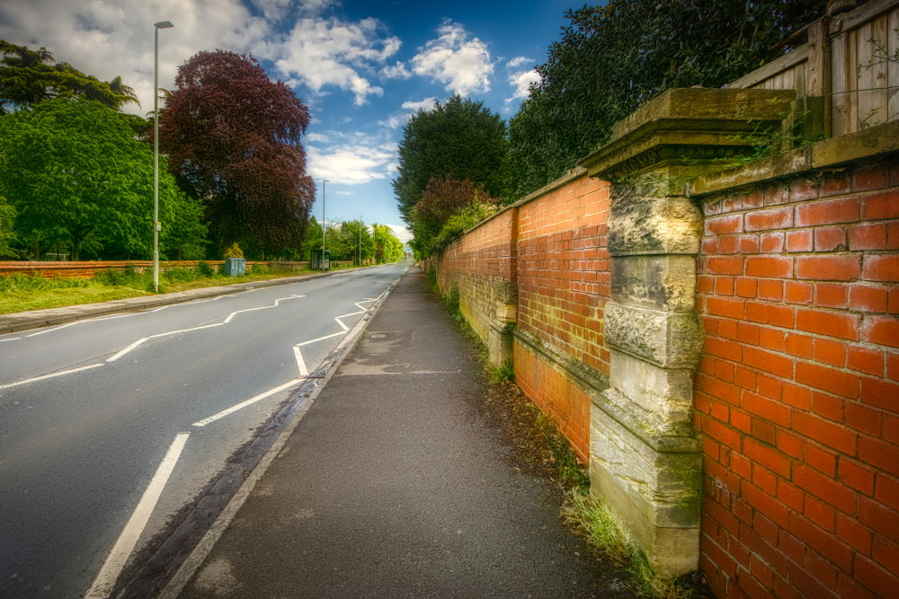 Roman Ermin Street in 21st-century form, the stone gate pillars in the wall surviving Barnwood House Hospital they once served